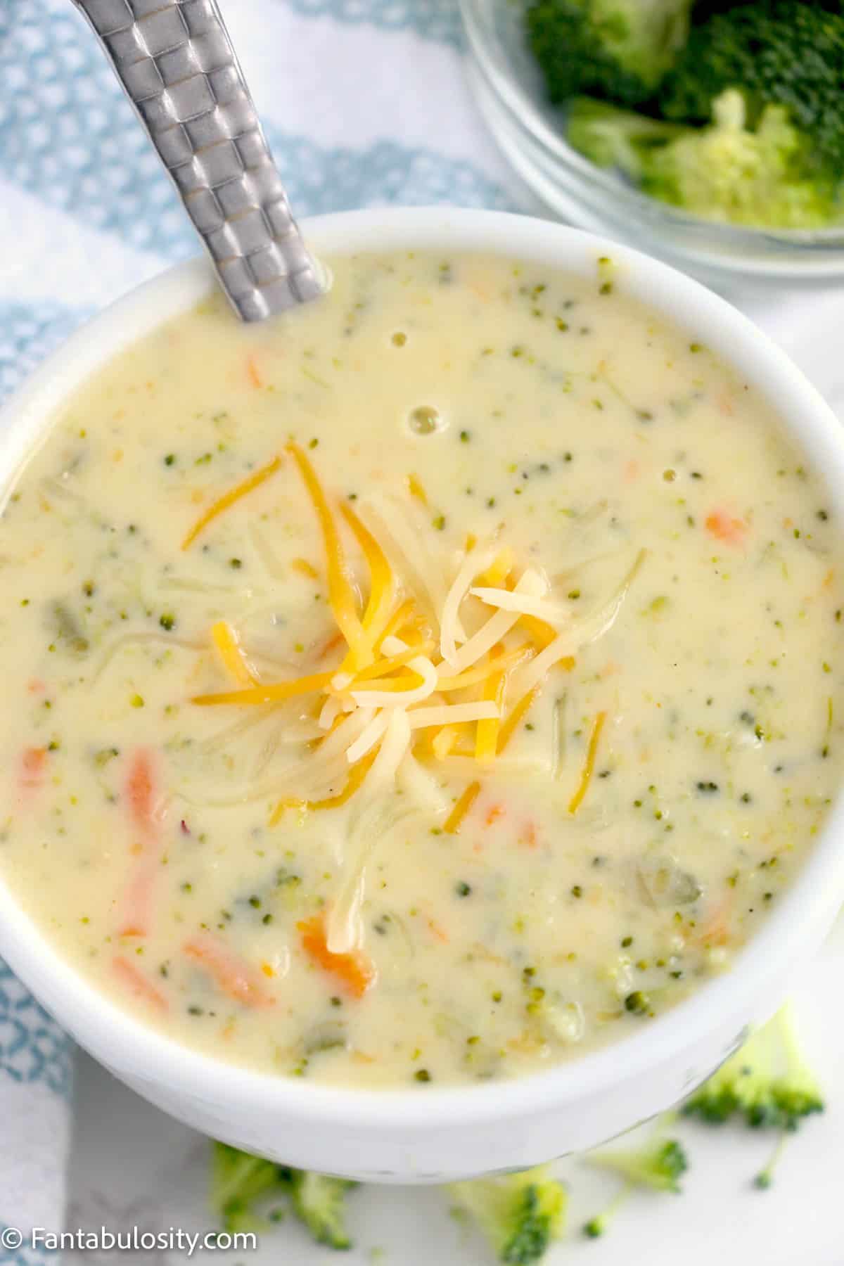 broccoli cheddar soup in a white bowl with spoon