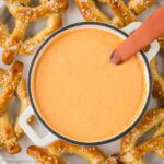Cheese dip in sauce pan, with soft pretzels surrounding it.
