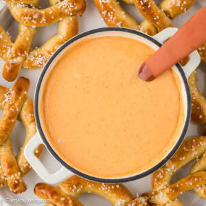 Cheese dip in sauce pan, with soft pretzels surrounding it.