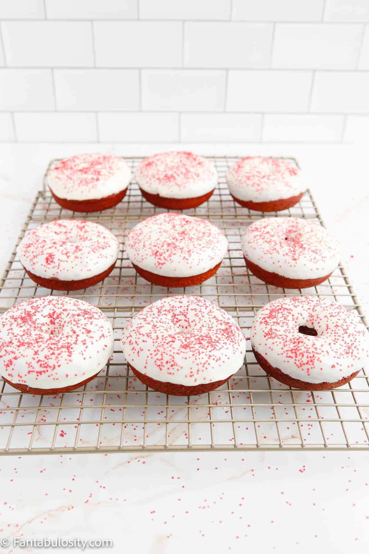 Iced red velvet donuts on a wire rack.