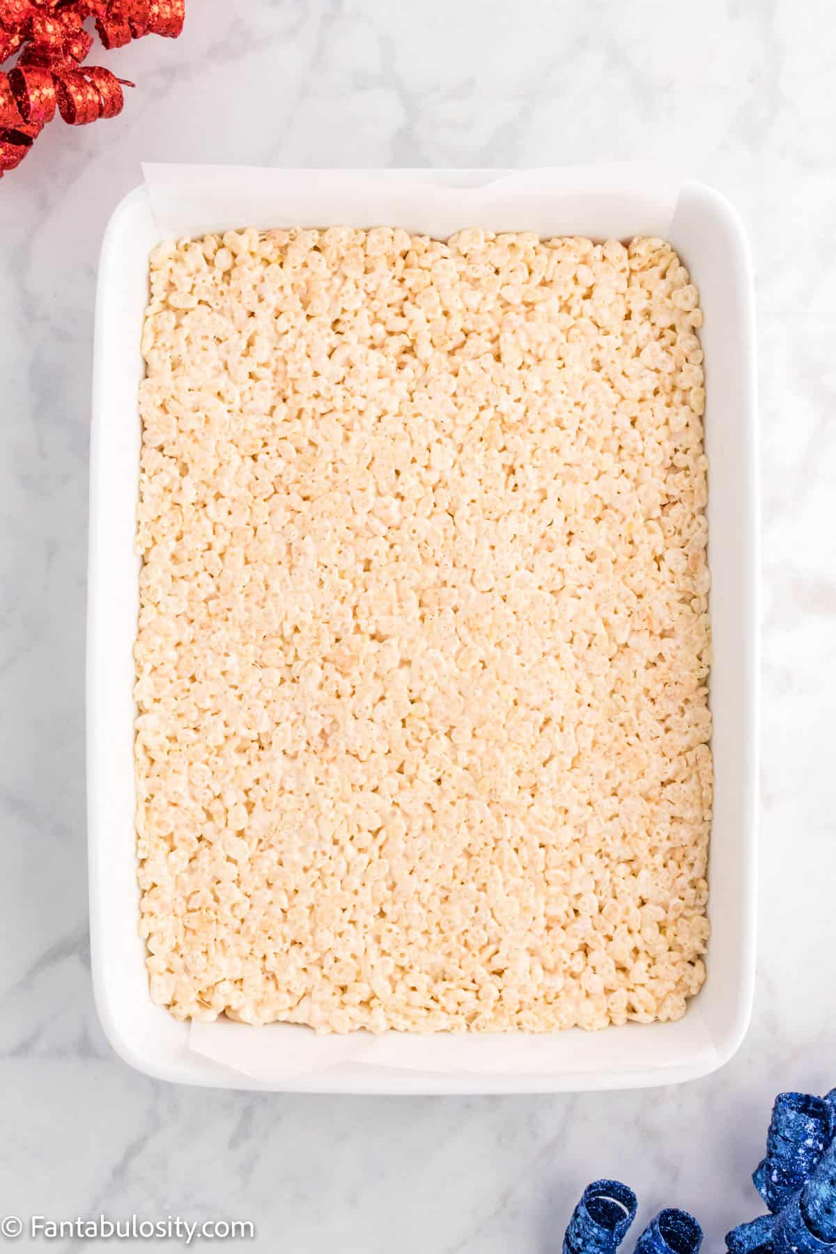 A white layer of Rice Krispies on top of the red layer in the 9x13 pan.