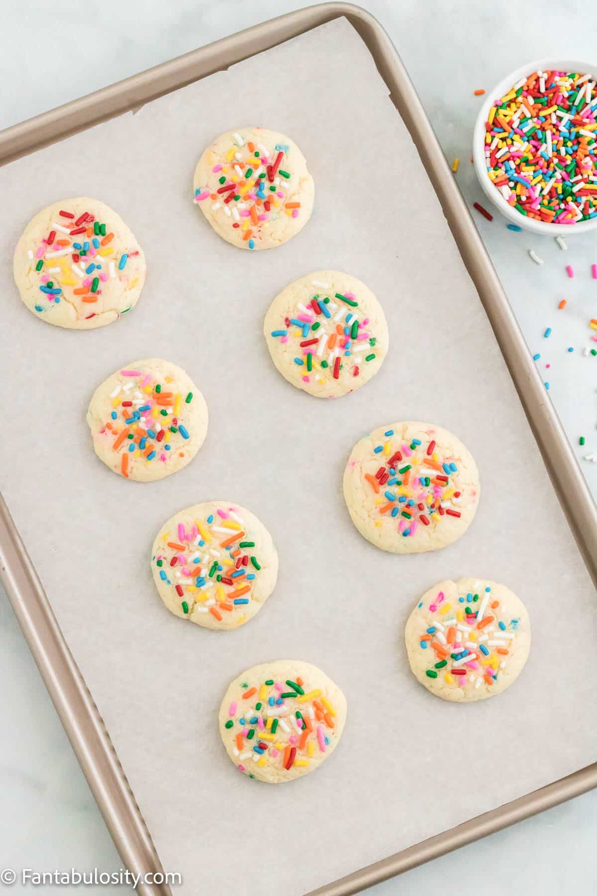 Baked funfetti cake mix cookies on a parchment lined baking sheet.