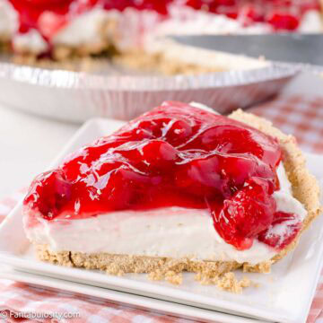 A slice of cherry cheesecake on a plate, next to full cheesecake.