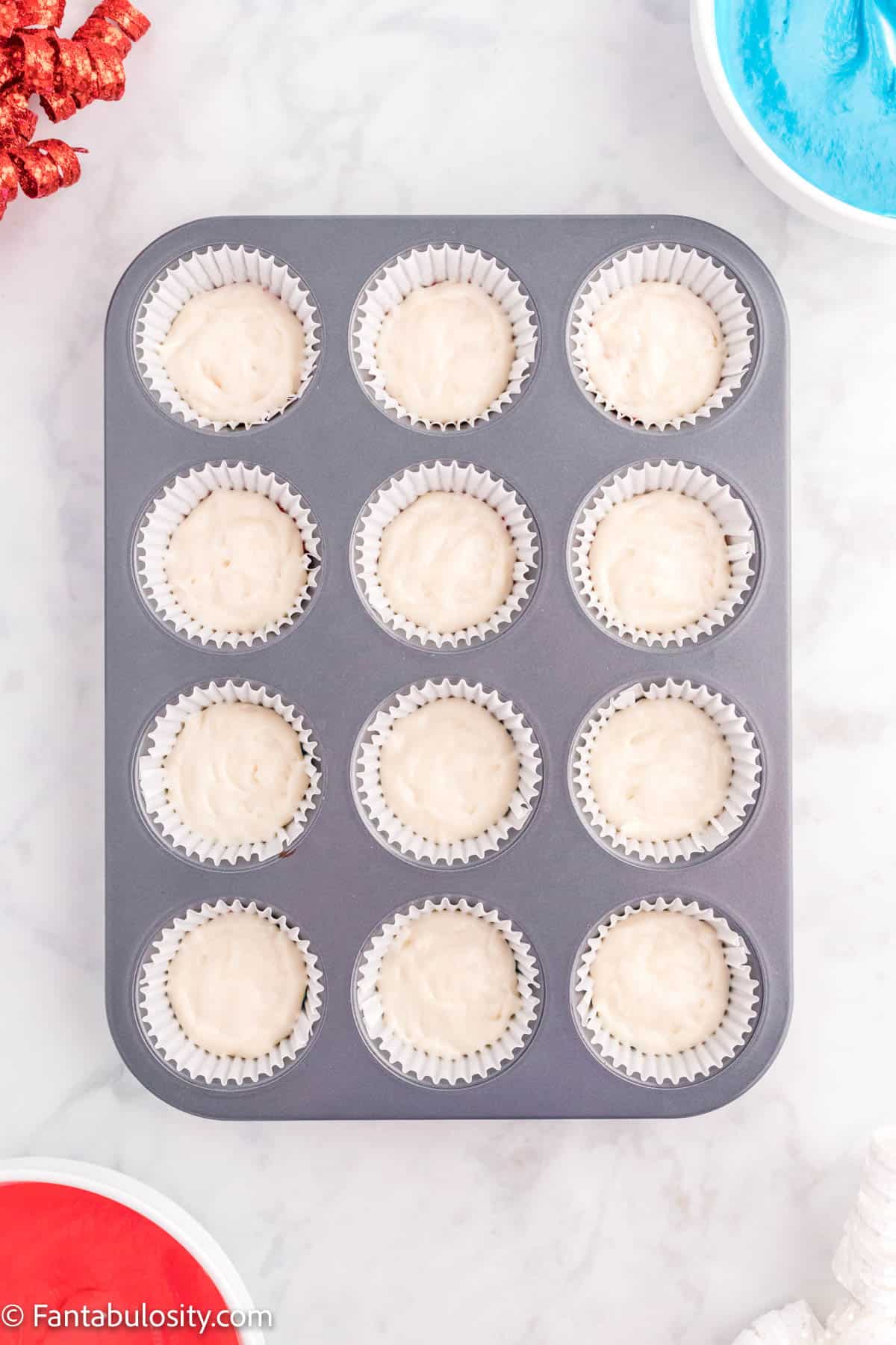 12 cupcake liners with white batter in them.