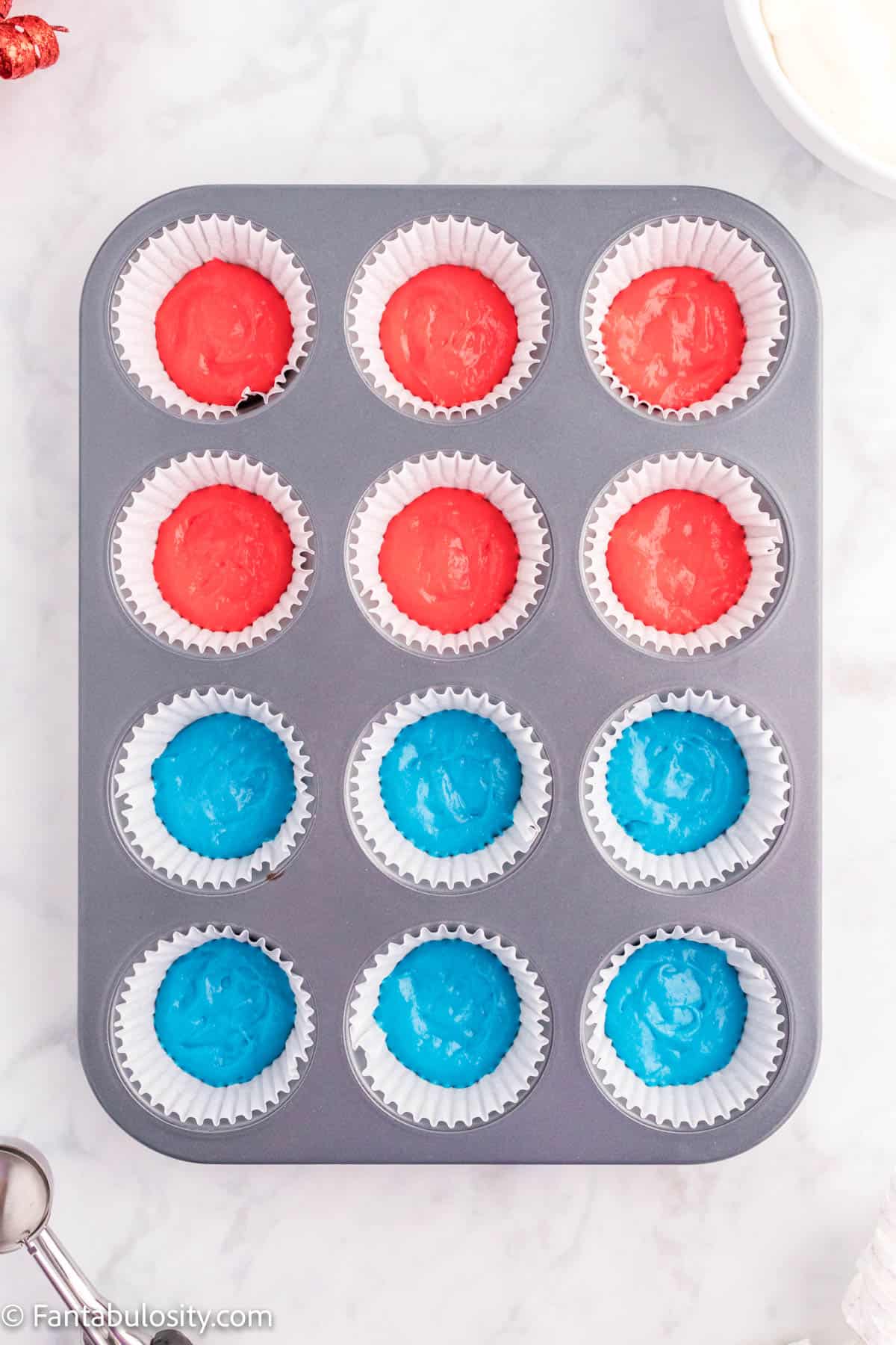 12 cupcake liners, 6 with blue batter and 6 with red batter in them.