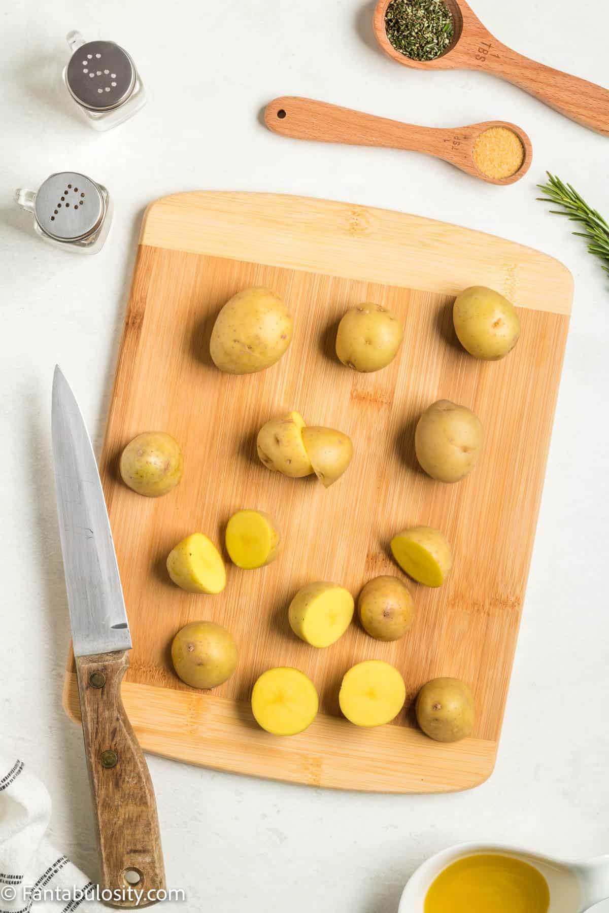 Baby potatoes on a cutting board. Some are cut in half, some are whole. 