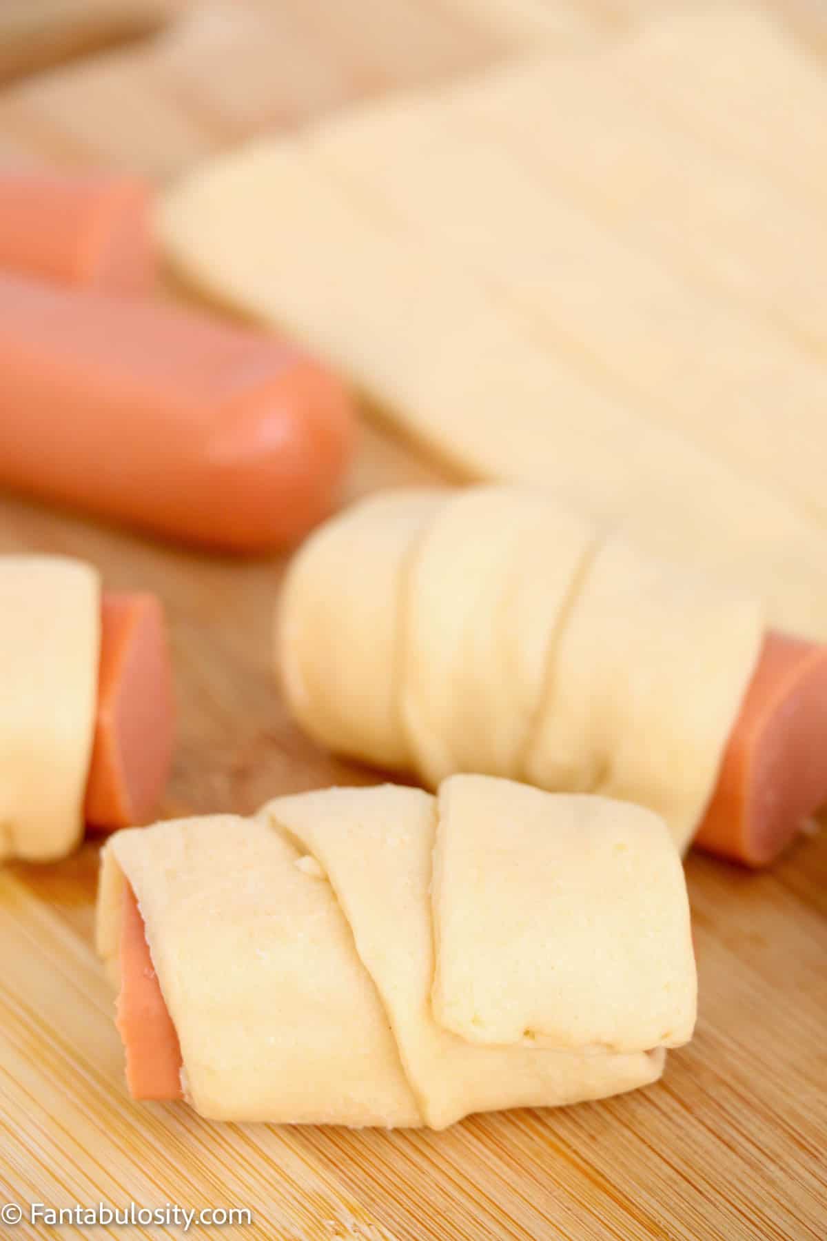 Hot dogs, cut in half and wrapped in a strip of crescent dough.
