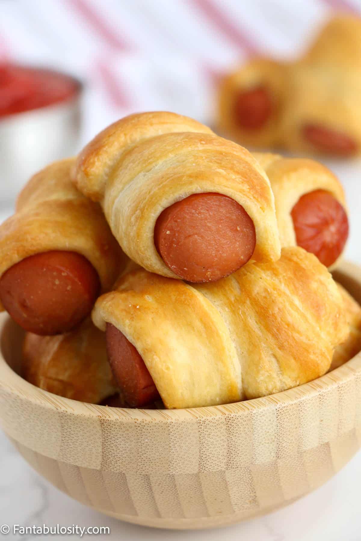 A plate with pigs in a blanket stacked on it.