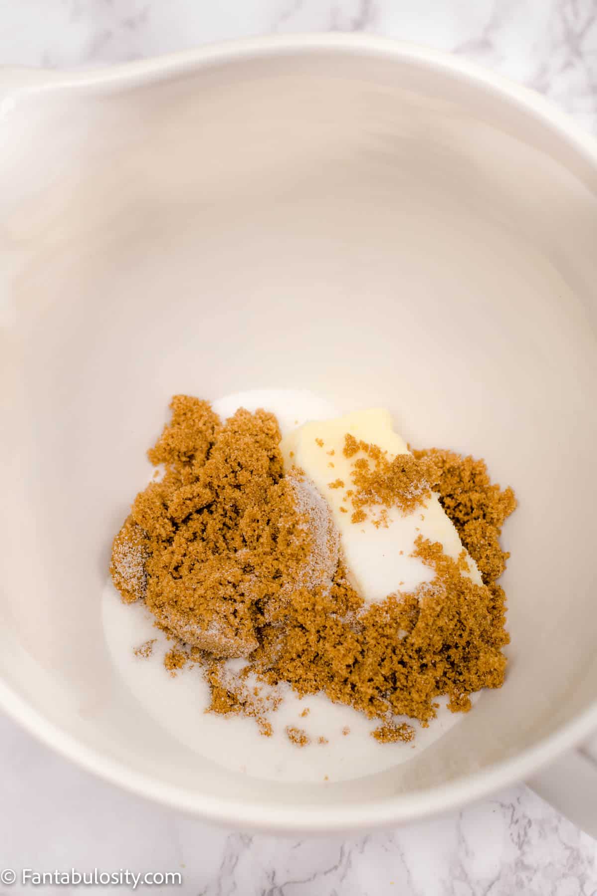 Butter, brown sugar and white sugar in a mixing bowl. 