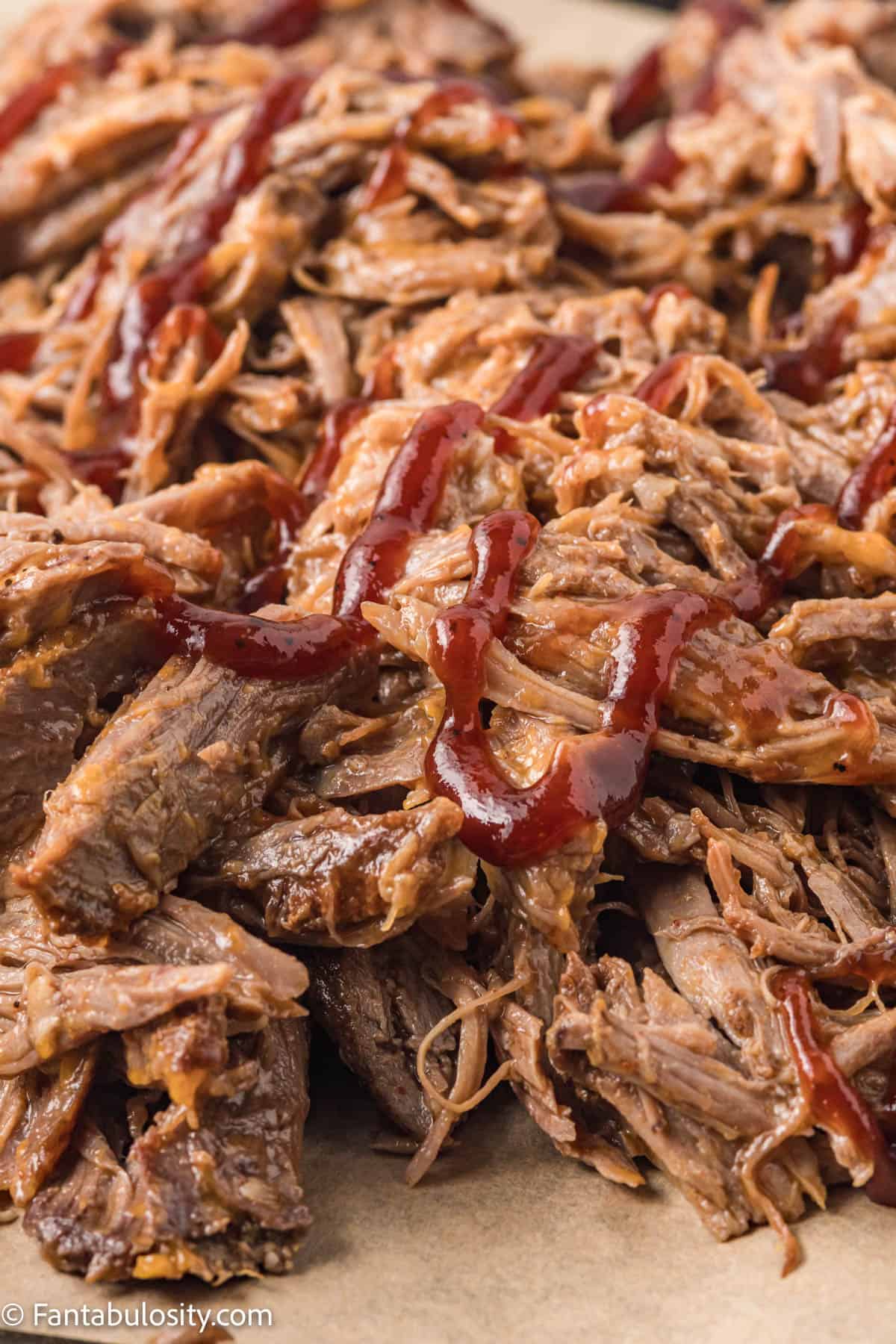 pile of slow cooker pulled pork with bbq sauce drizzle