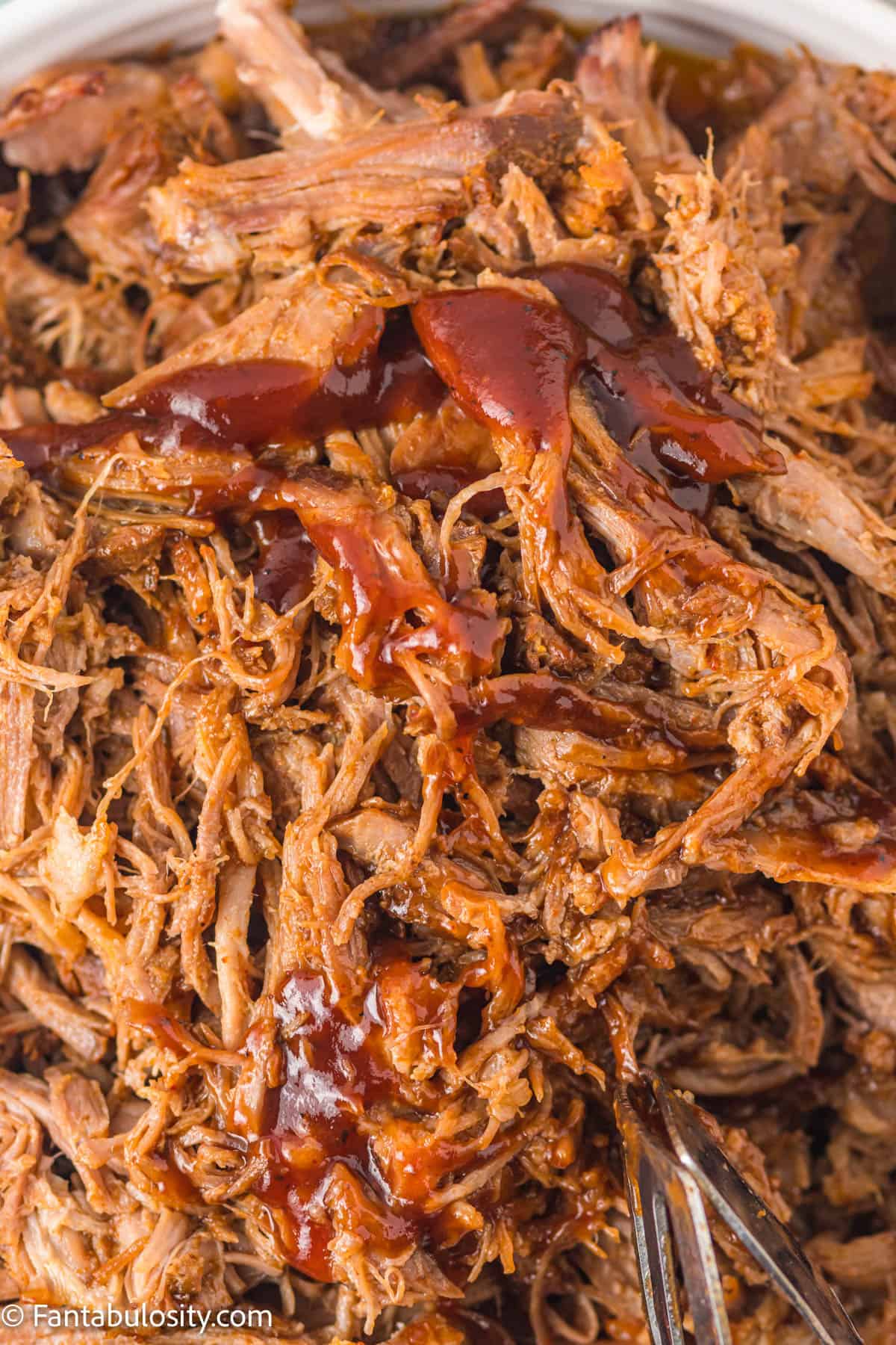Pulled pork in bowl with bbq sauce drizzled on top