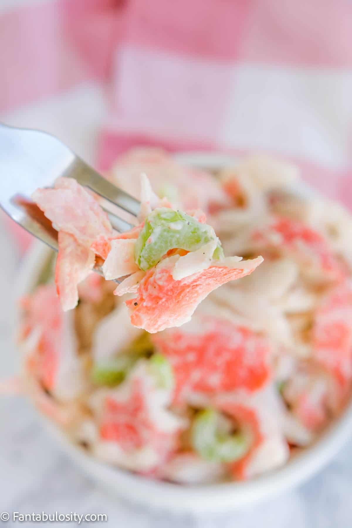 bite of crab meat salad on fork, holding above bowl of salad