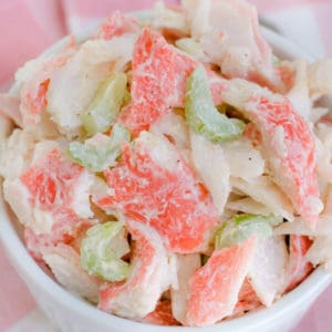 close up of bowl of crab salad on a pink napkin