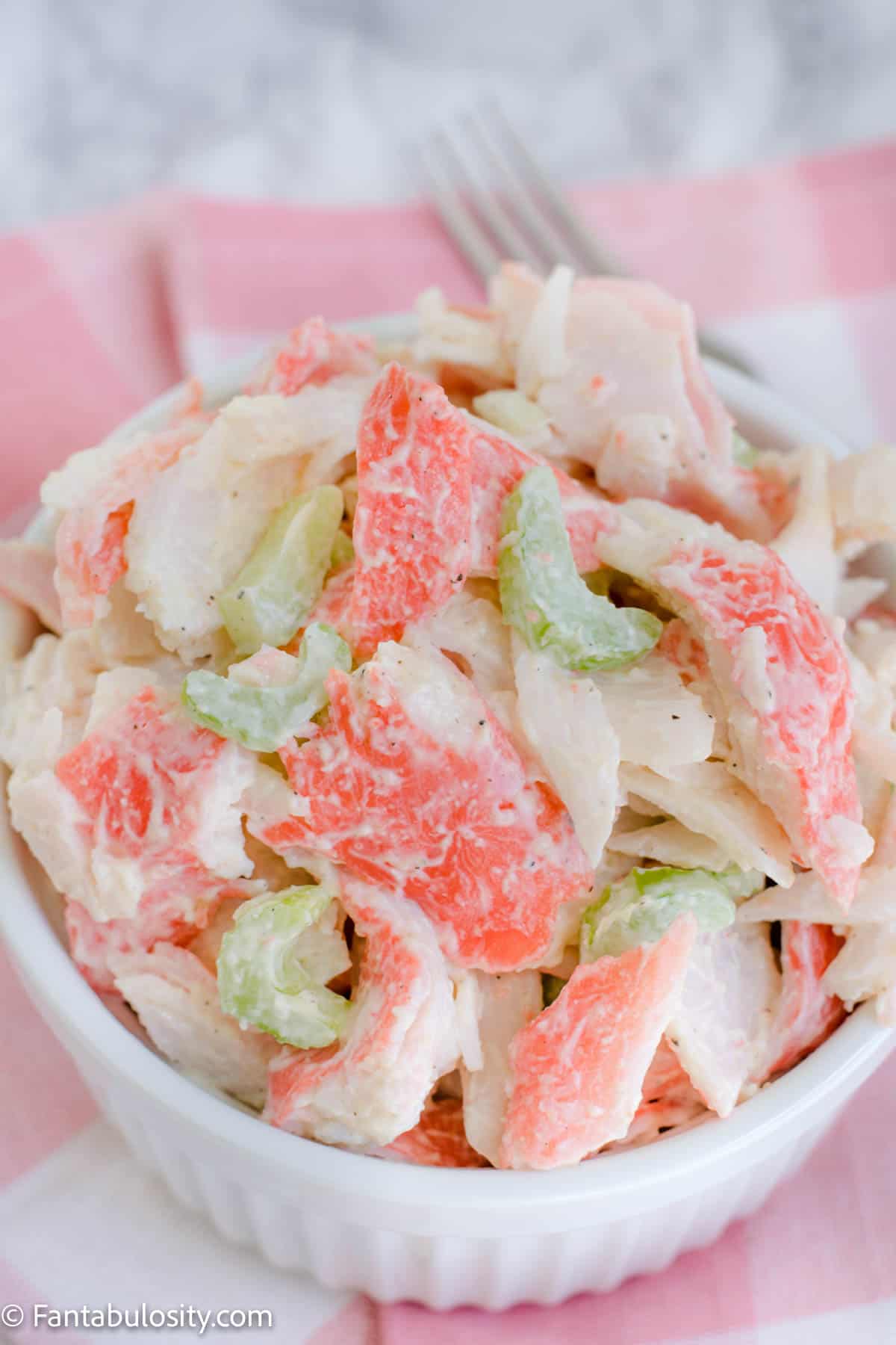 crab salad in white bowl with pink napkin underneath