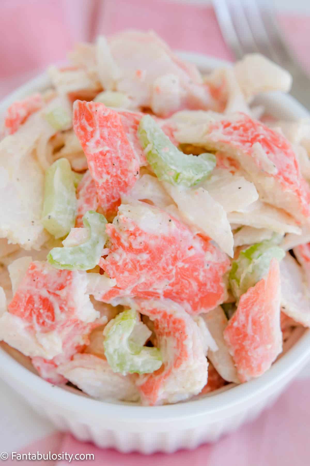 imitation crab salad in white bowl with pink napkin in background