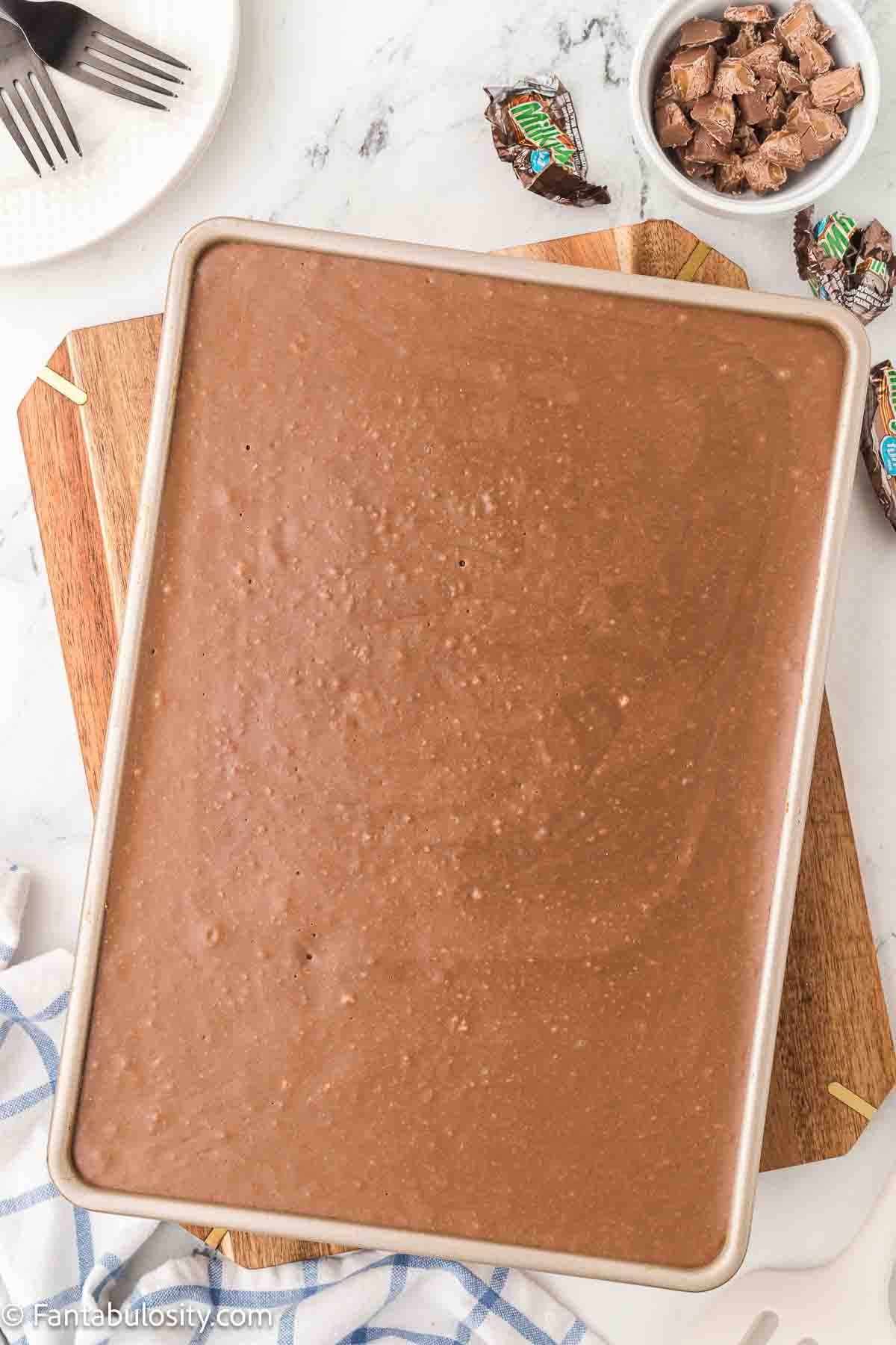 Melted chocolate frosting poured on top of Milky Way cake. 