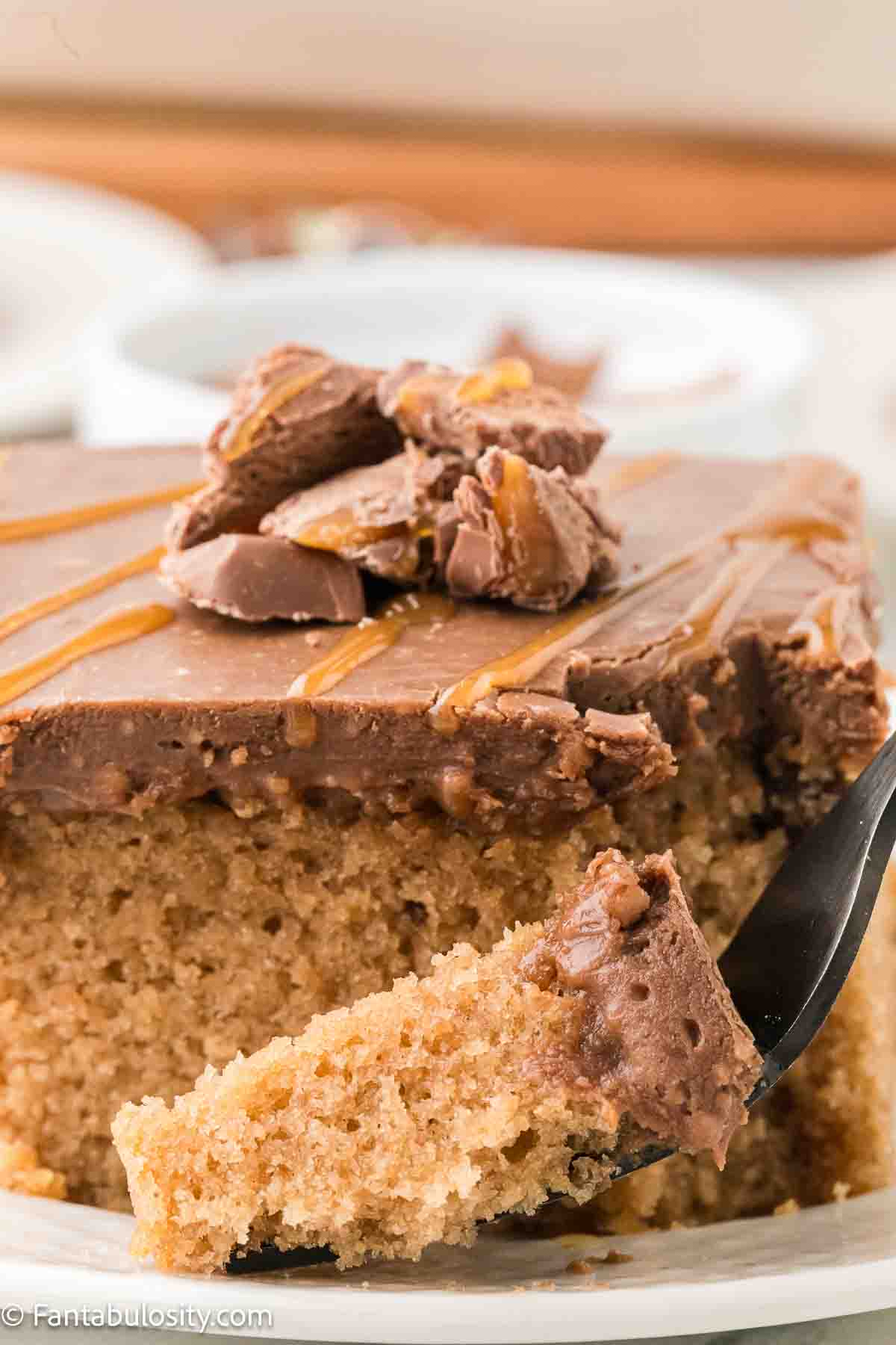 A slice of Milky Way cake on a plate, that has a fork sitting next to it. 
