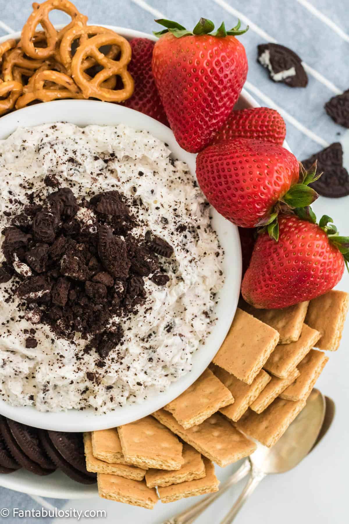 Oreo dip with graham crackers, strawberries and cookies around it.