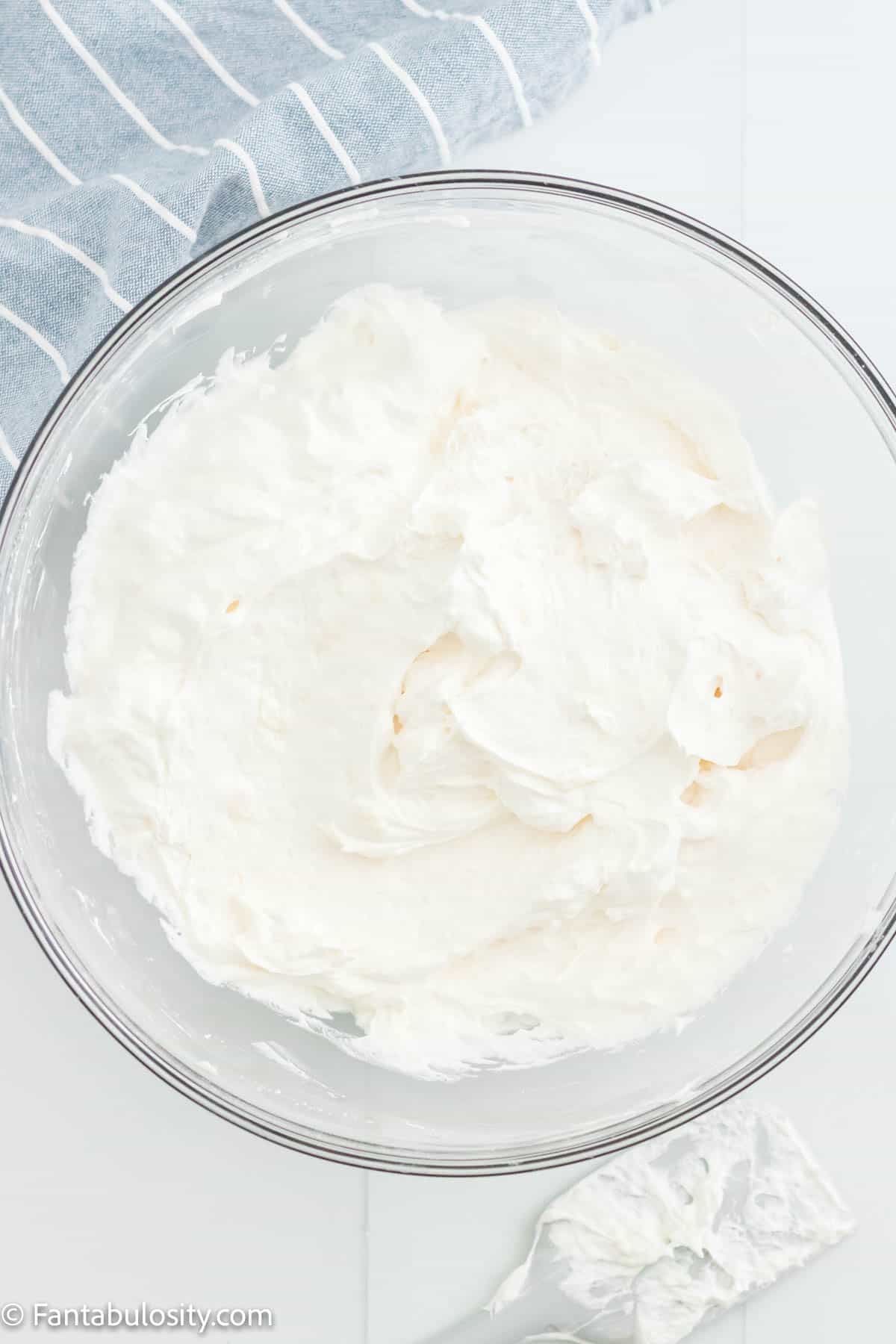 Whipped topping in a bowl with the cream cheese, powdered sugar, and vanilla. 