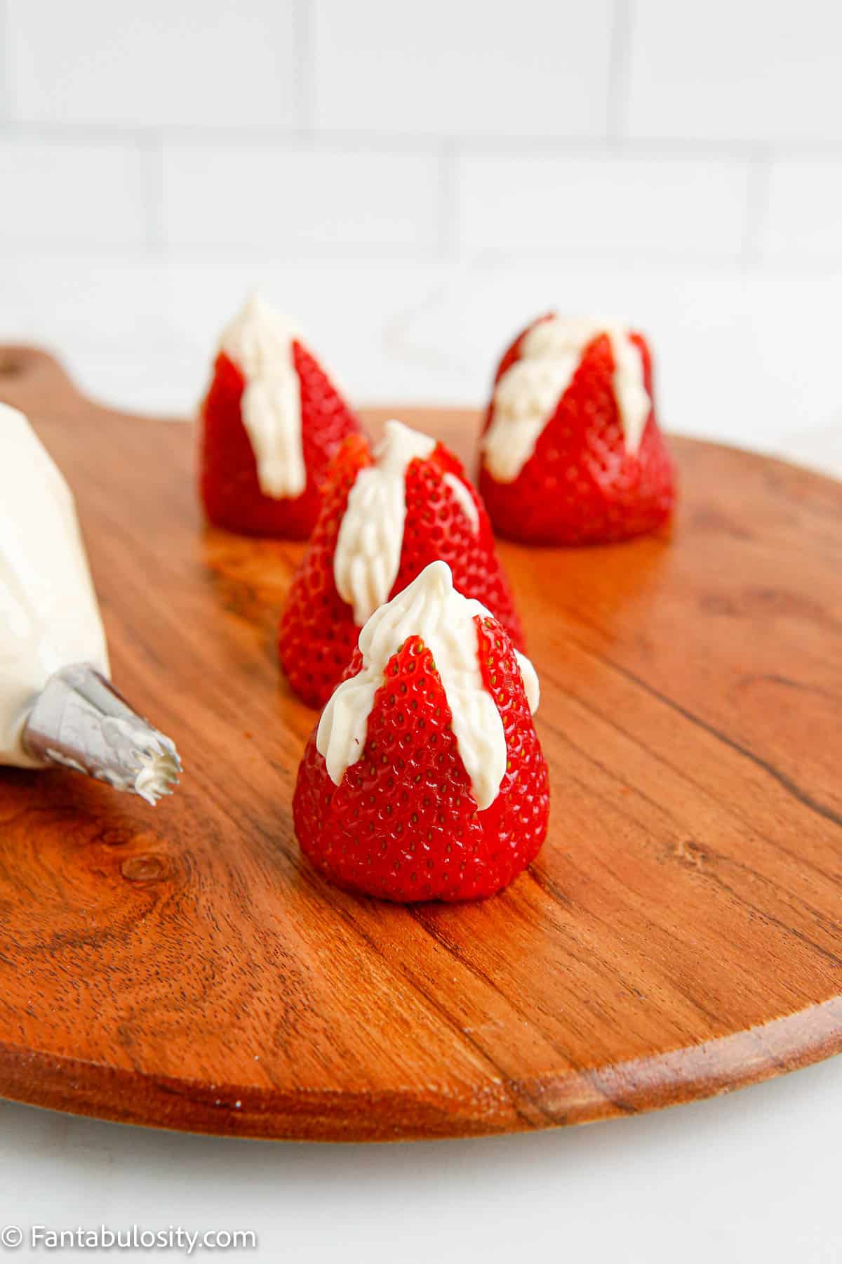 Piped strawberries with cream filling on cutting board