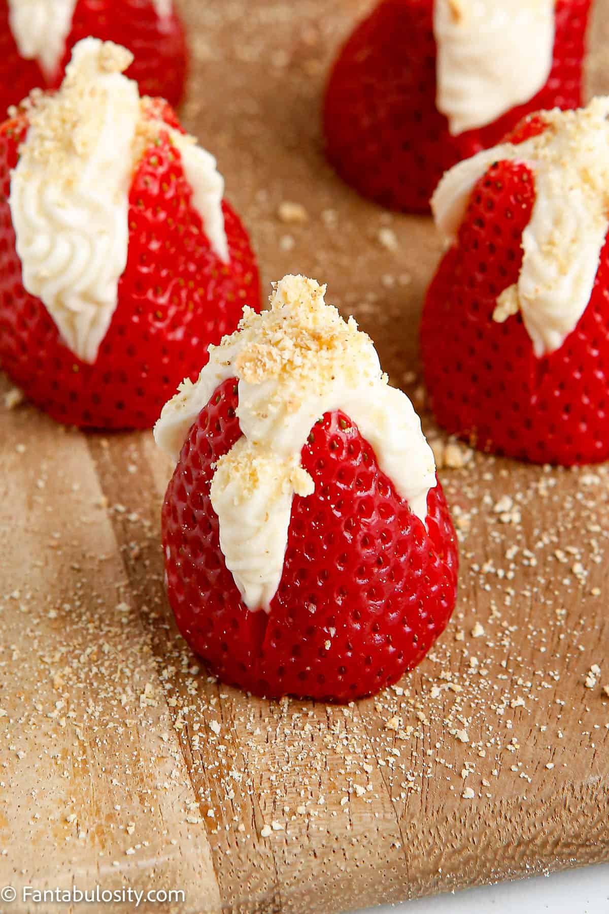 strawberries on cutting board, that are filled with cheesecake filling