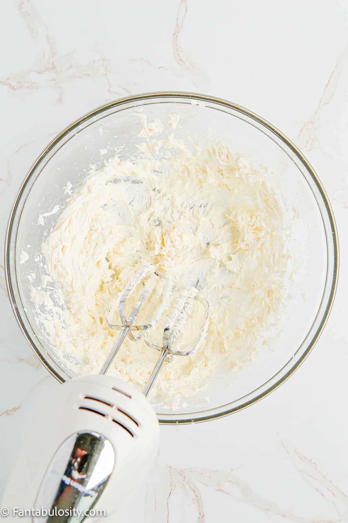 cream cheese beaten in glass bowl with mixer