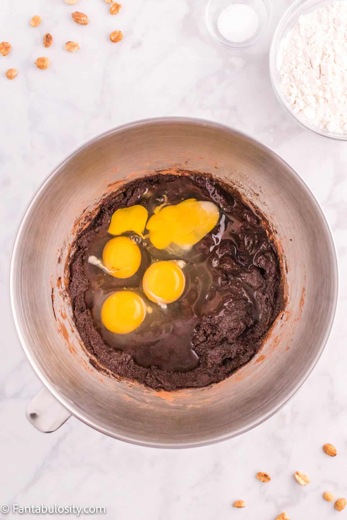 Eggs added to brownie batter in the bowl of a stand mixer.