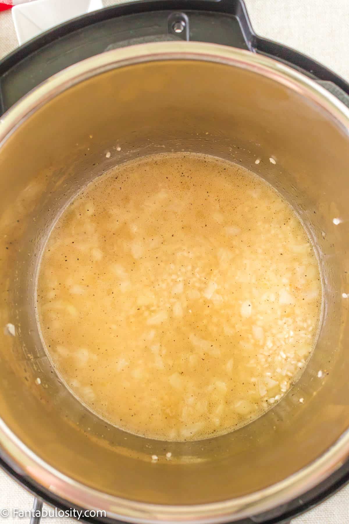Rice, chicken broth, and spices in the Instant Pot.