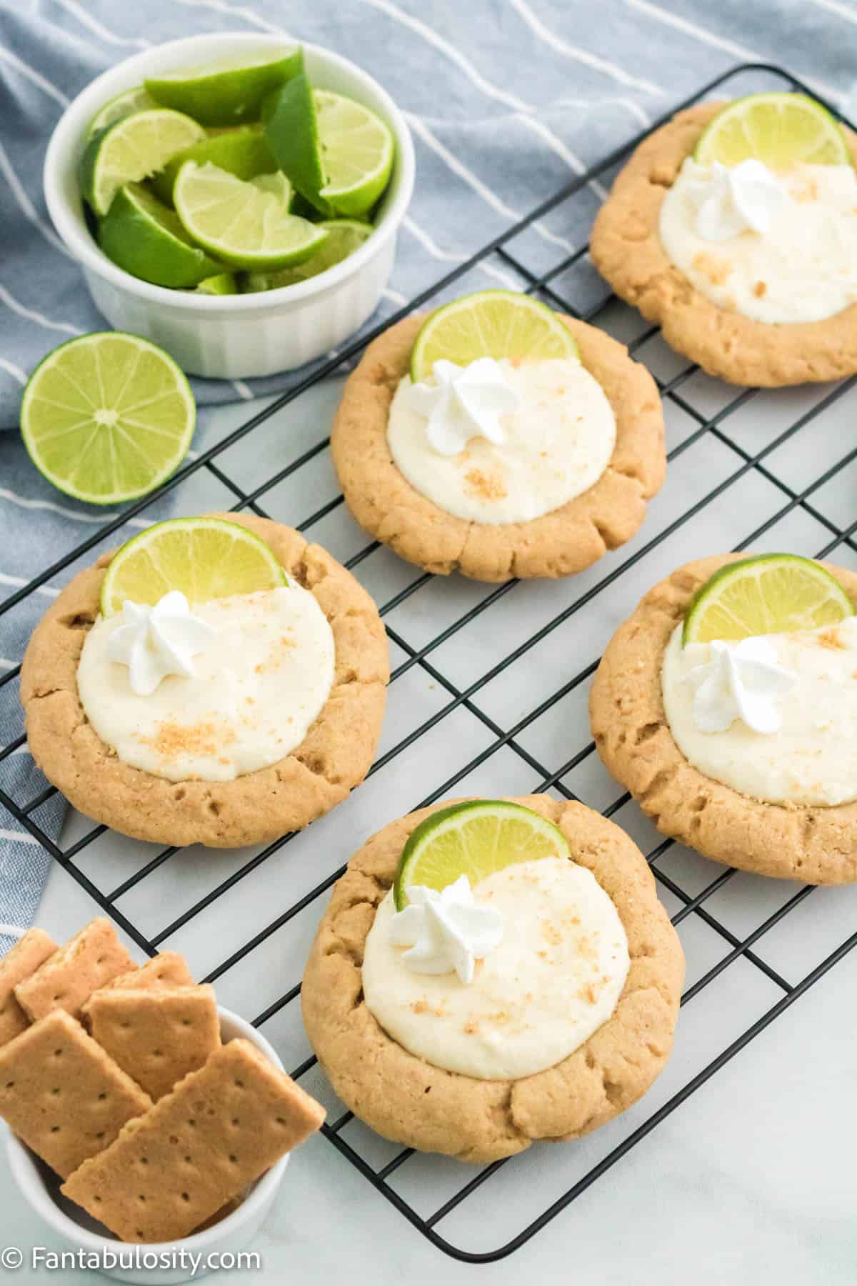 Key lime pie cookies, fully garnished, sitting on a wire cooling rack.