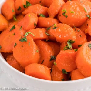 Close up of cooked carrots covered in a butter brown sugar glaze and garnished with fresh parsley