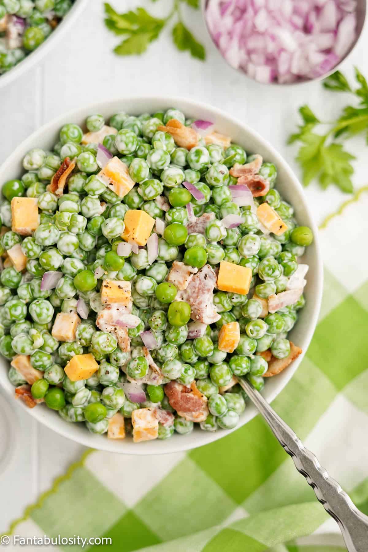 pea salad in white bowl with spoon sticking out