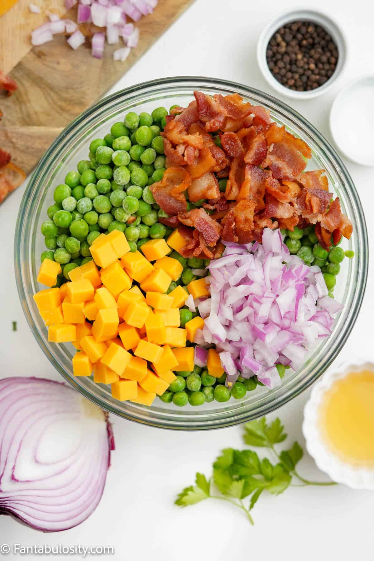 Peas, bacon, onion, and cheese in a bowl.
