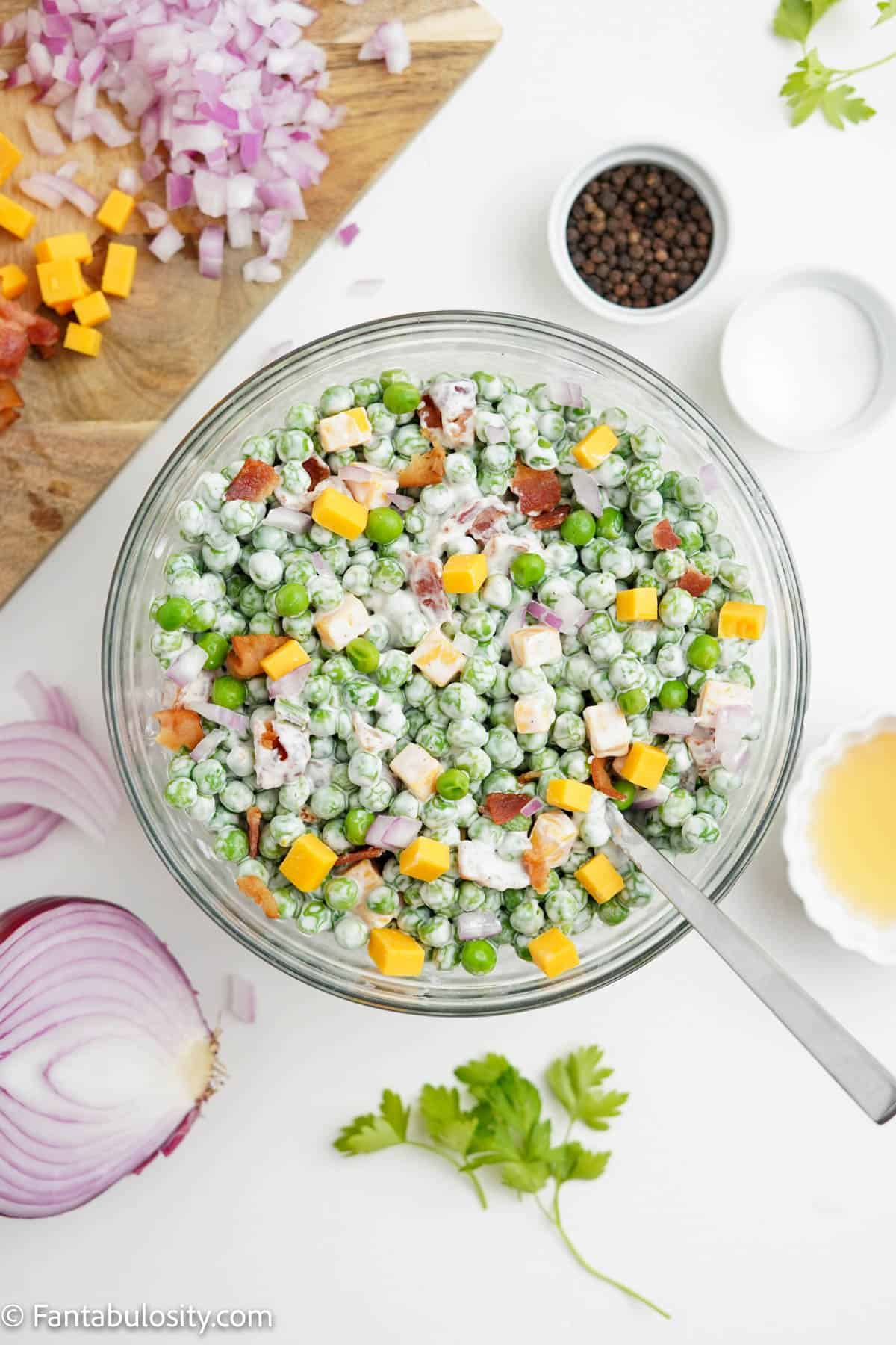 Pea salad being mixed together in a bowl.
