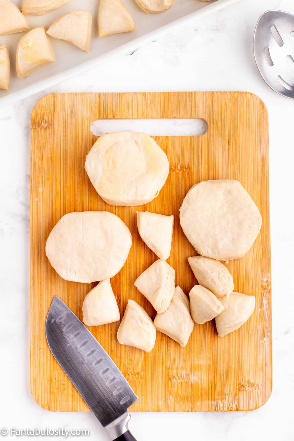 Biscuits on a cutting board being cut into pieces.