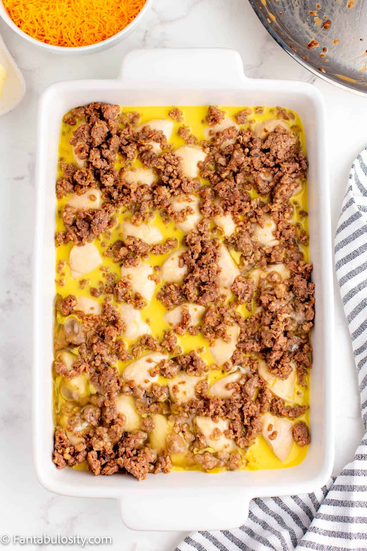 A 9x13 casserole dish with biscuits, sausage, cheese, and egg mixture in it.
