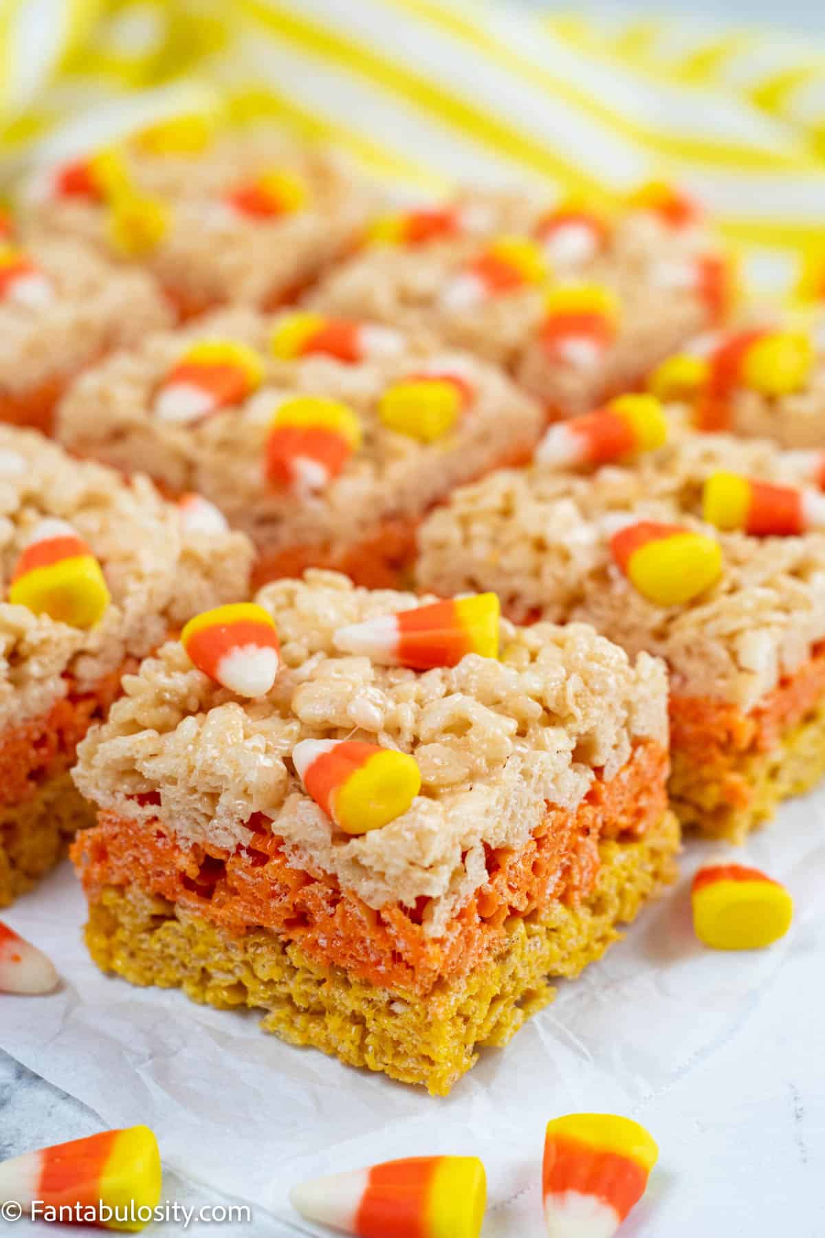 Close up of the a candy corn rice krispie treat, showing the yellow, orange and white layers of the treat