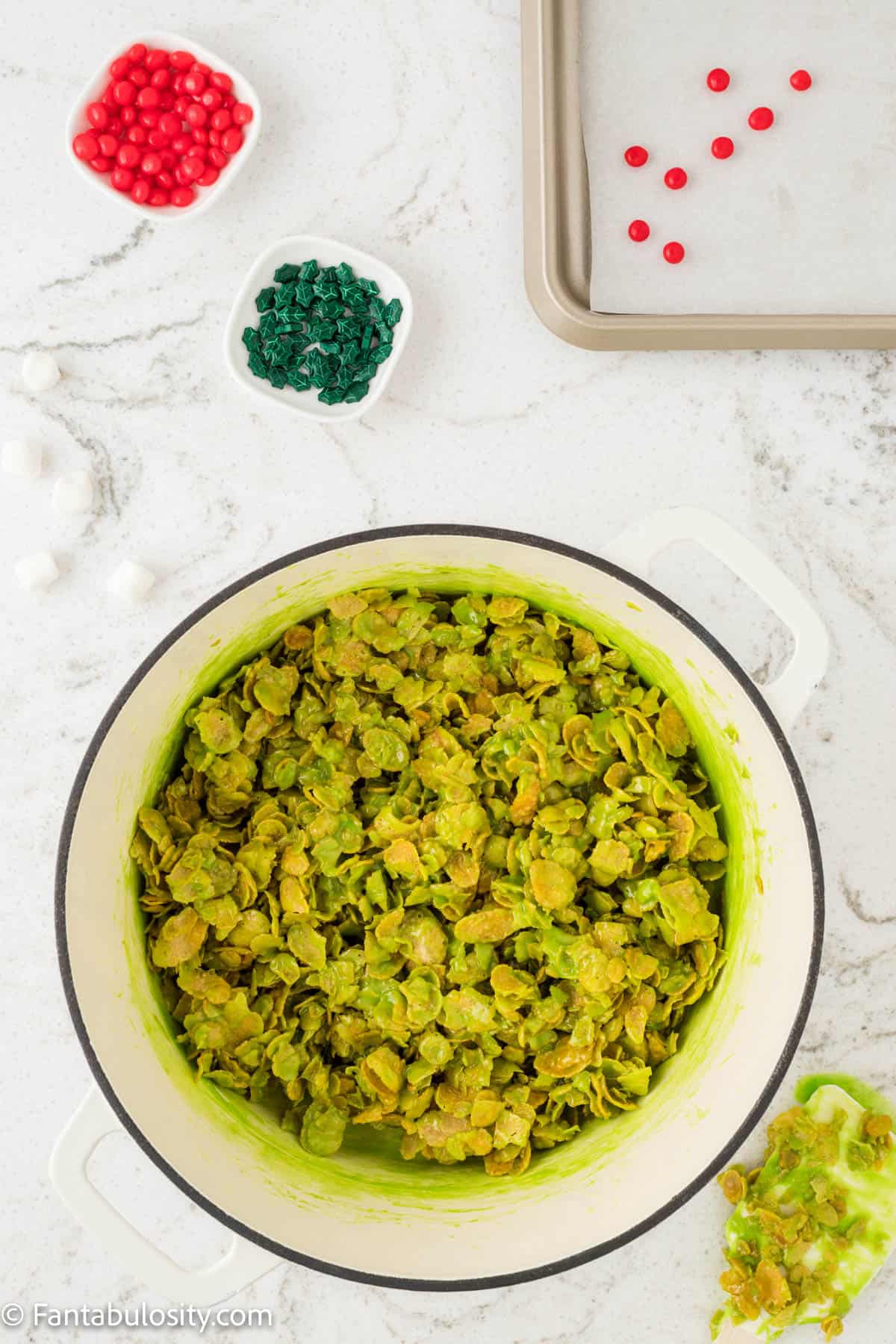 Green marshmallow coated cornflakes have been stirred in a large pot and will be shaped into no bake cornflake wreath cookies