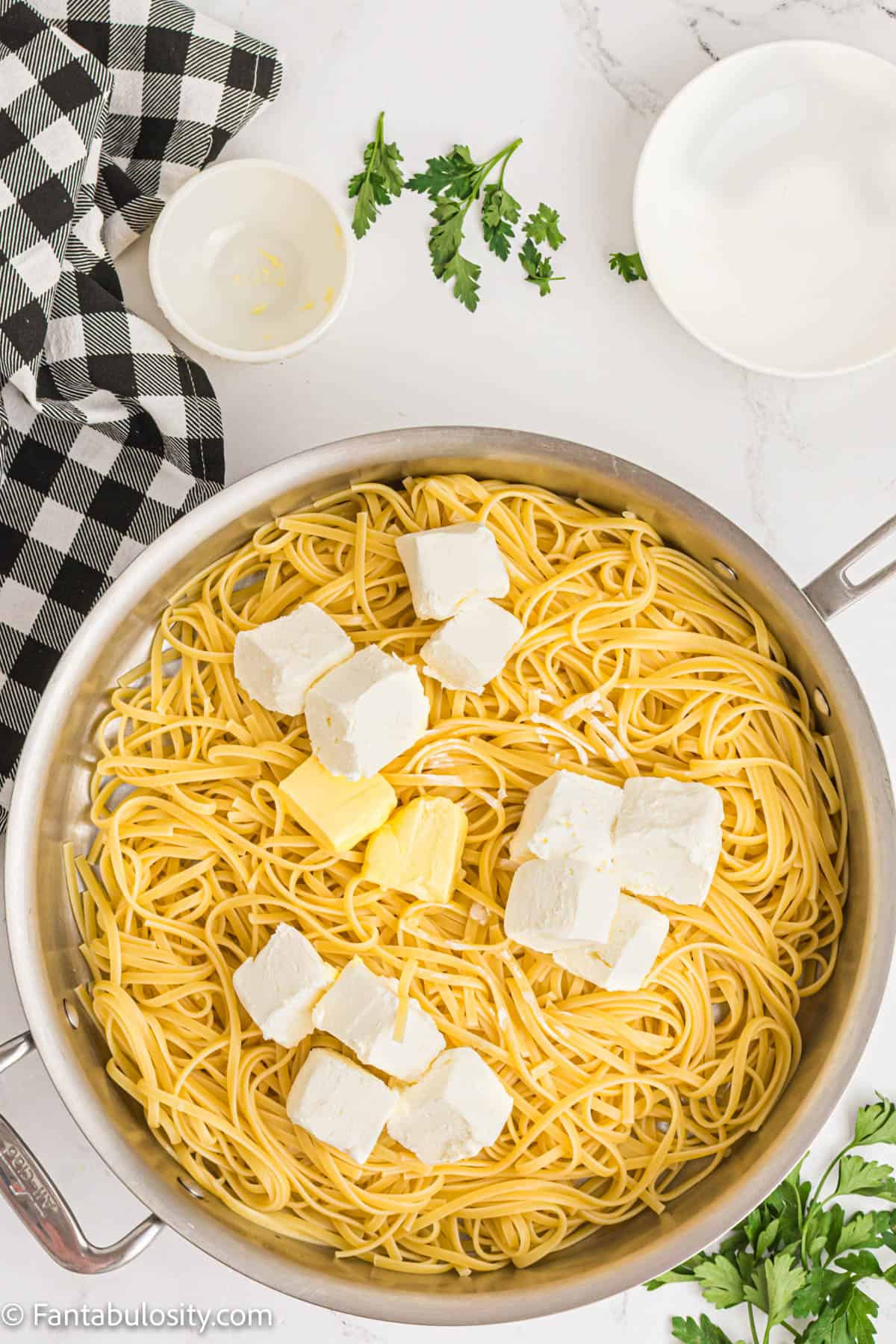 Linguine noodles, butter, and cream cheese in a pot. 