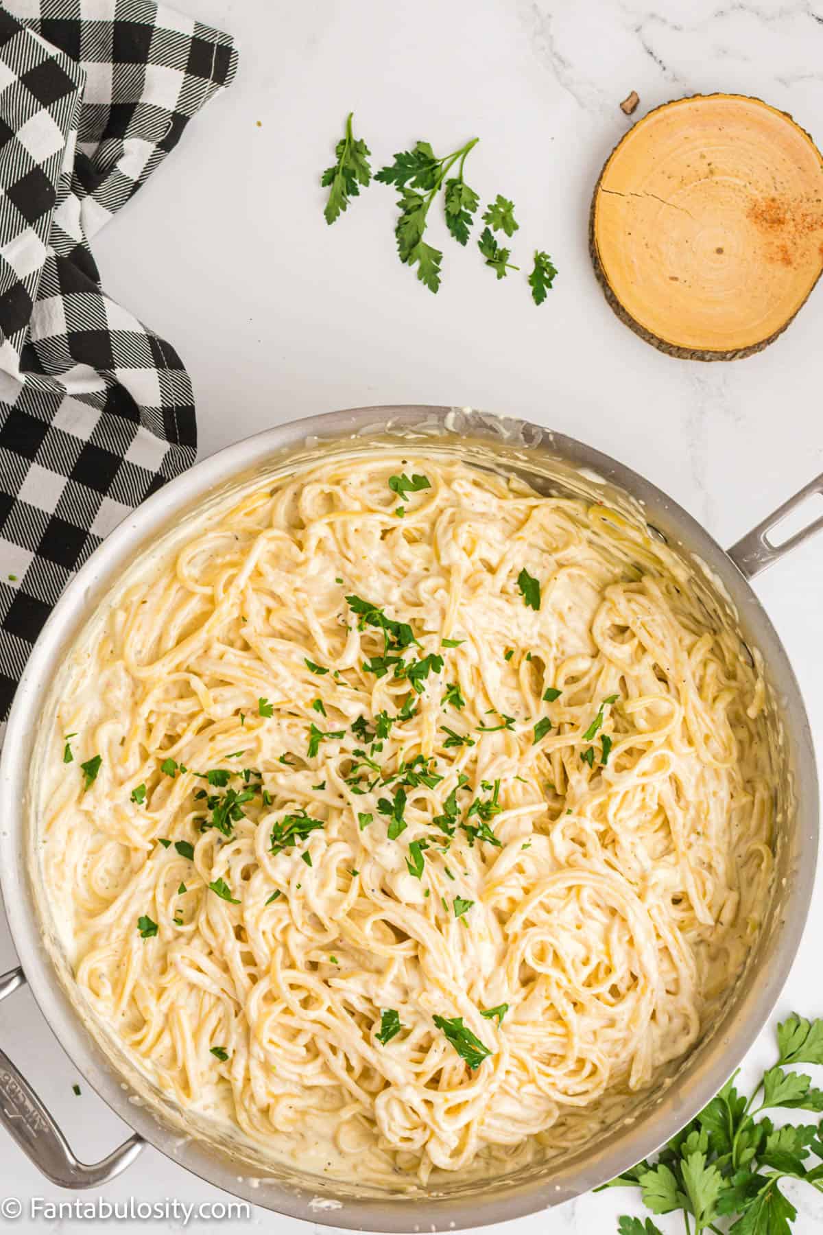 Cream cheese pasta in a pot with fresh chopped parsley sprinkled on it. 