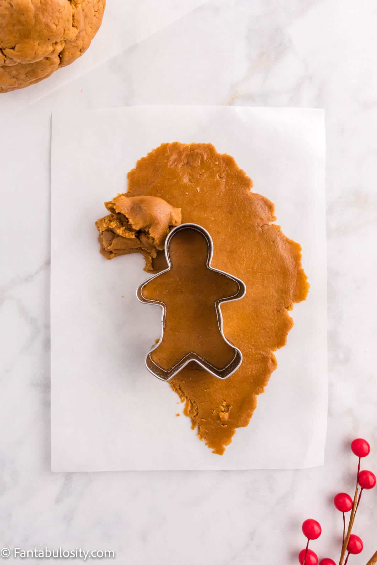 Gingerbread dough is being removed from around a cookie cutter to reveal the shape made from a cookie cutter