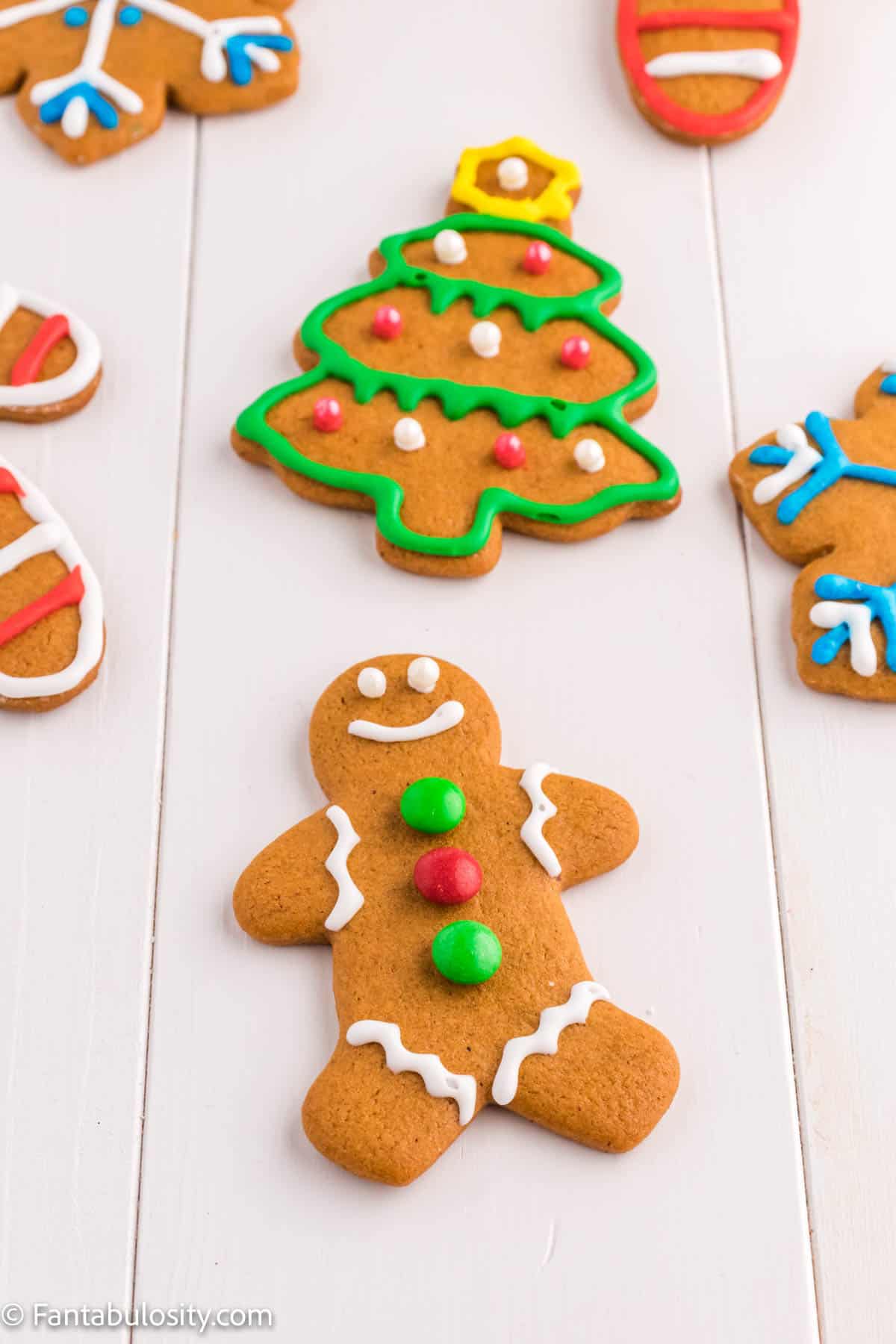 Brightly piped and decorated Christmas cookies shaped like gingerbread, snowflakes, trees and candy canes are displayed on a white background