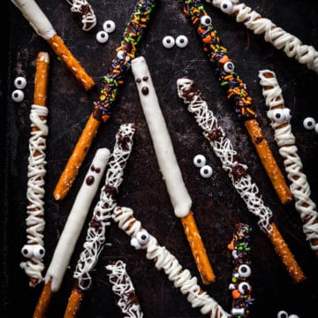 Pretzel rods decorated for Halloween are dislayed on a black marbled background