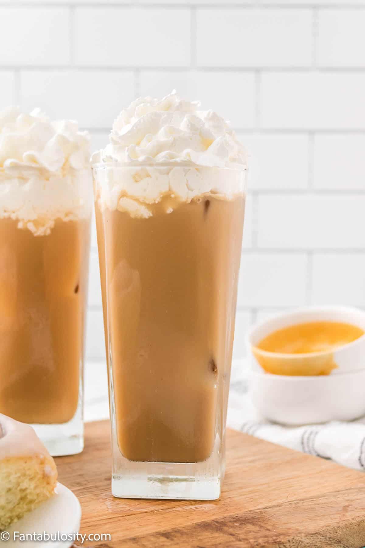 Two glasses of iced caramel latte have been topped with whipped cream