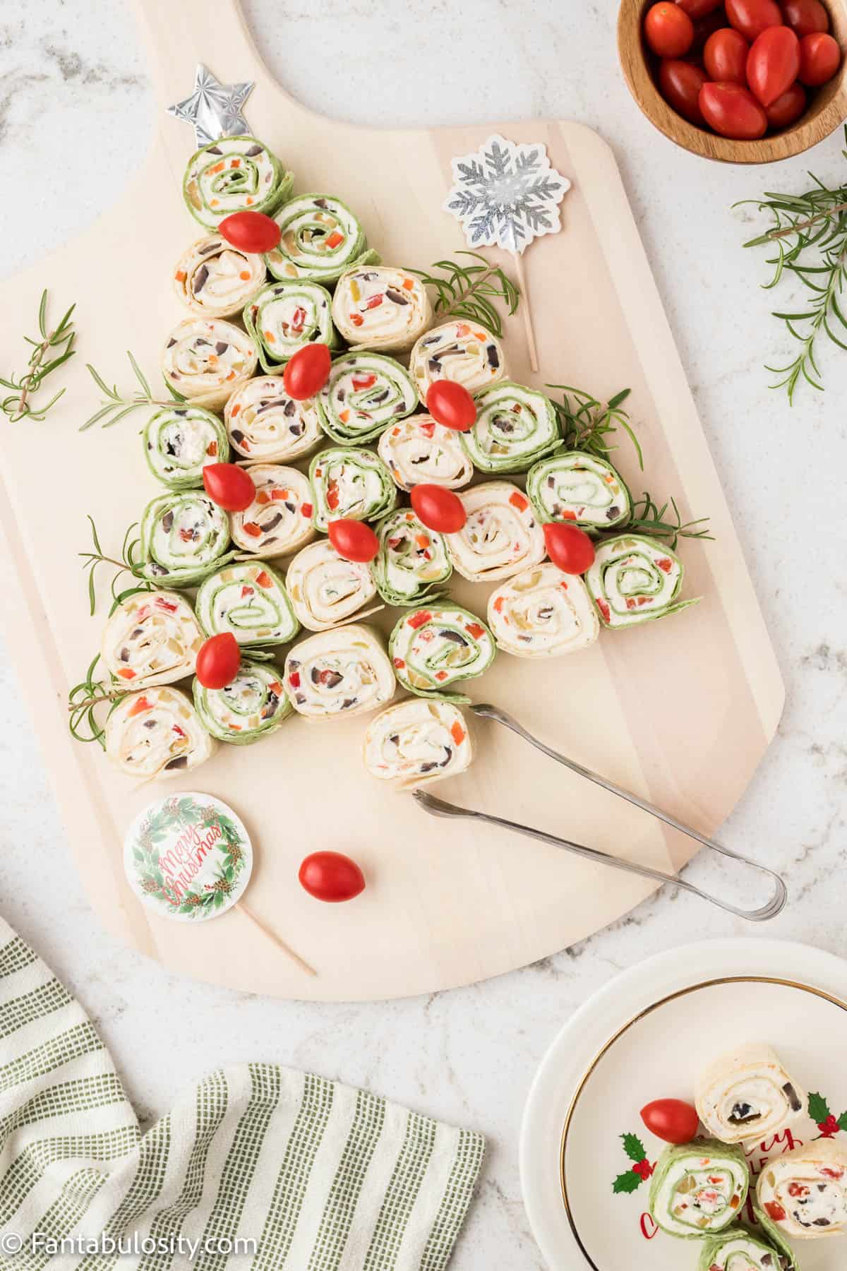 A wooden serving board holds a Pinwheel Christmas tree appetizer