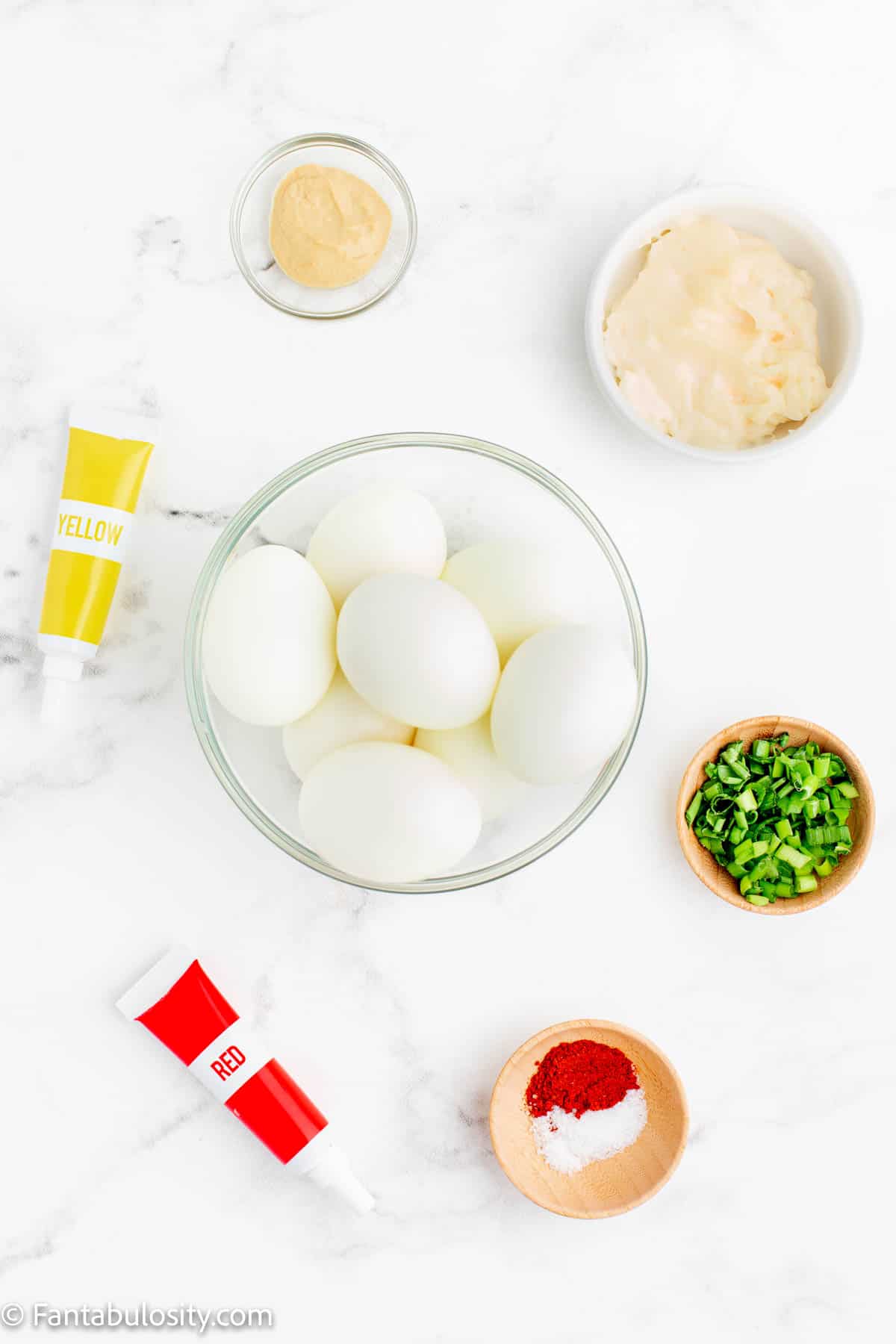 The ingredients to make Pumpkin Deviled Eggs are displayed on a white marble background