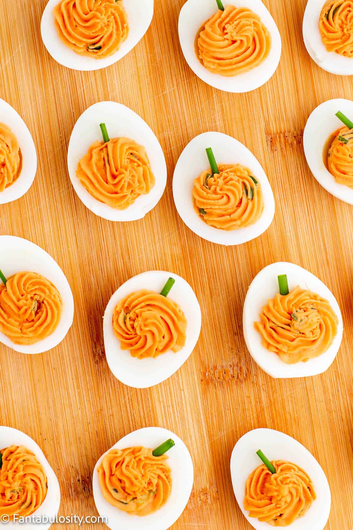 Pumpkin Deviled Eggs are displayed on a wooden cutting board