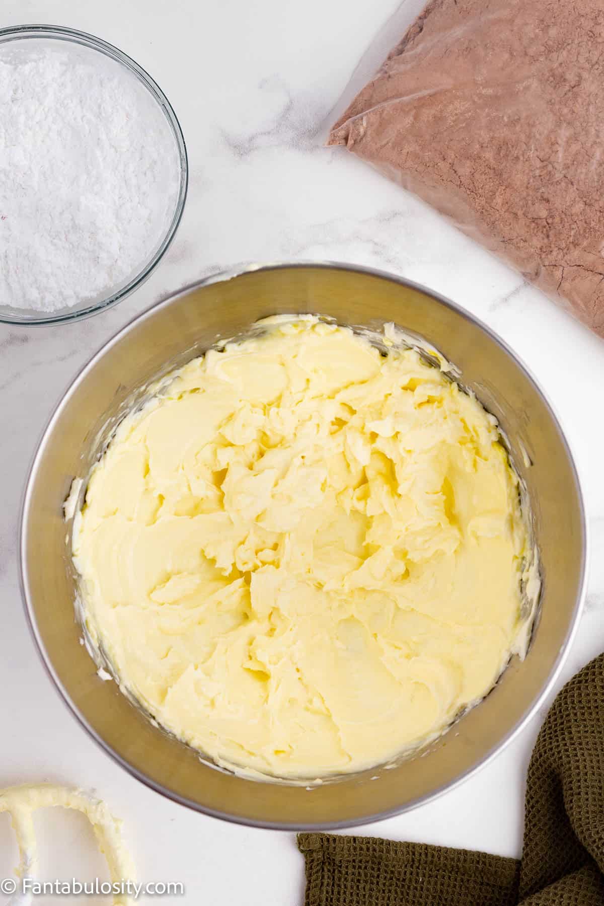 A light yellow creamy mixture is shown in a large metal mixing bowl