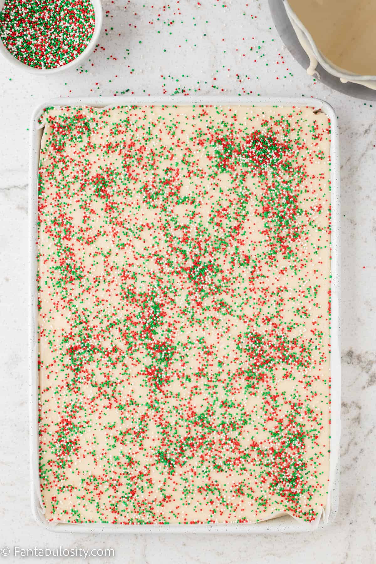 A 9x13 pan is filled with white chocolate fudge topped with red, white and green sprinkles