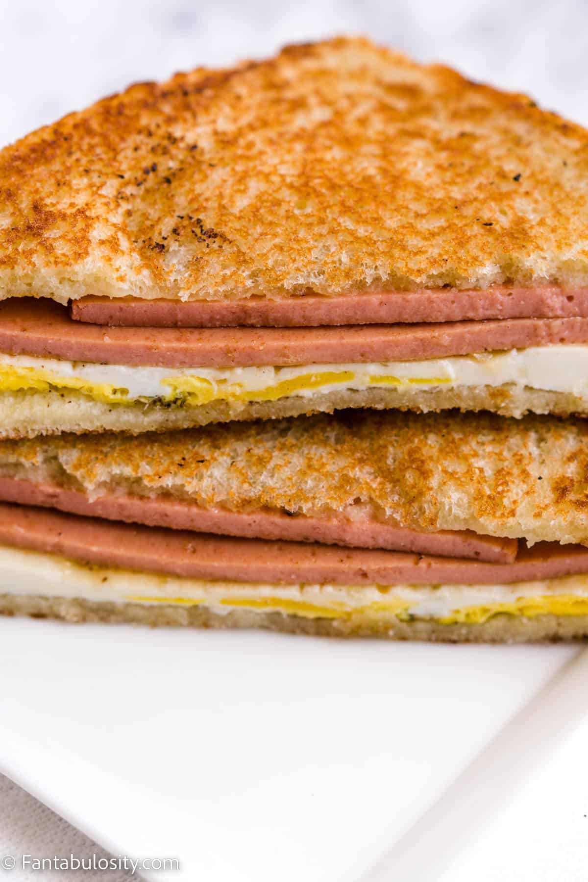 Fried bologna and egg sandwich on white plate