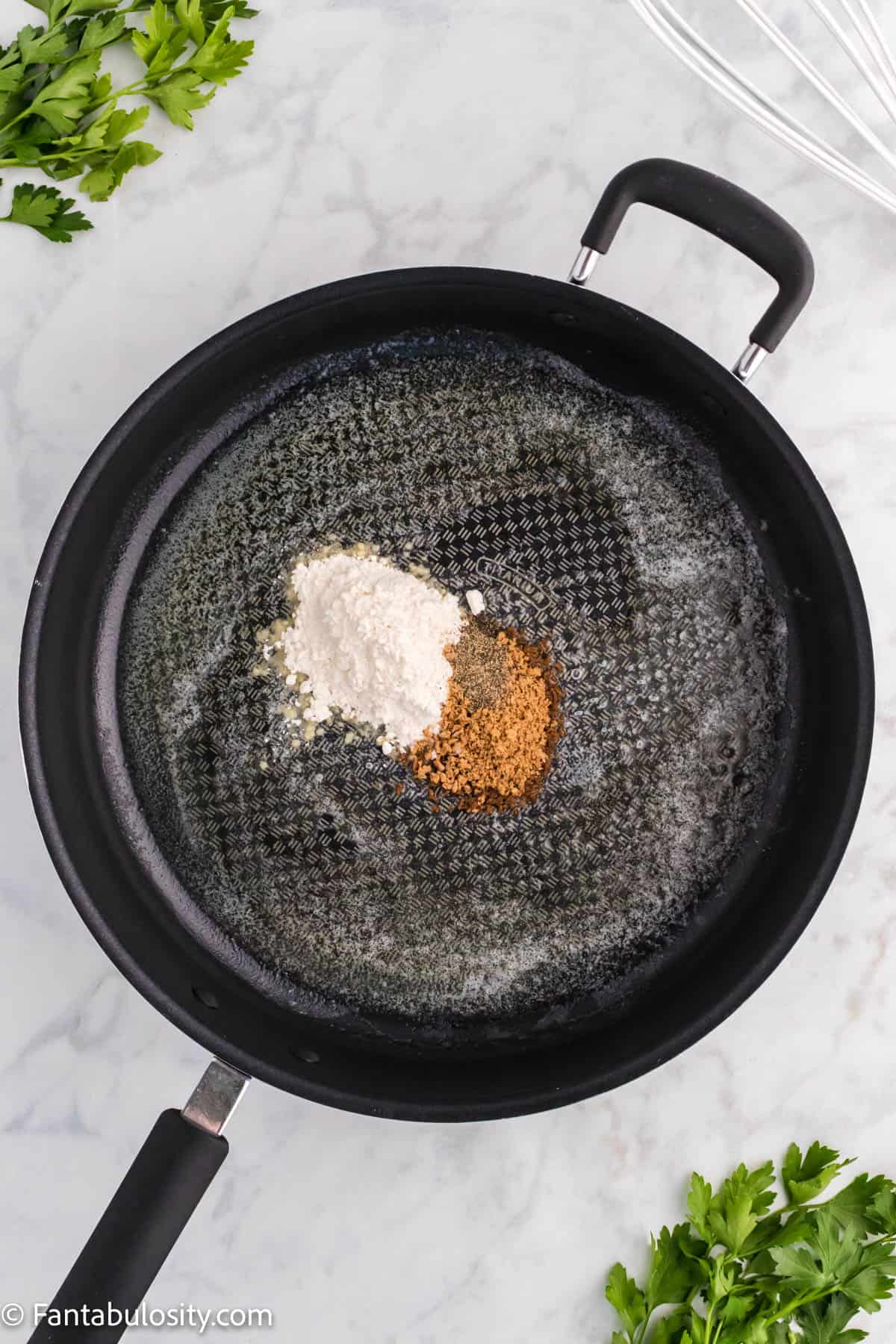 A large black skillet has melted butter, flour and nutmeg